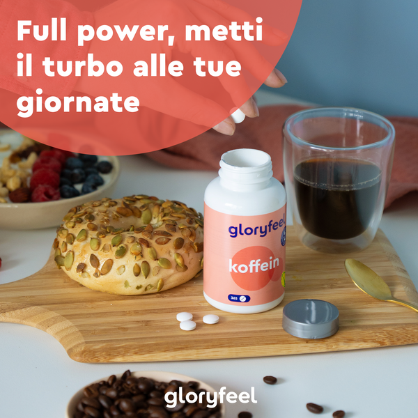 Un bagel, caffè e bacche sono appoggiati su una tavola di legno con una bottiglia di gloryfeel Italia Caffeina e pillole. Il testo sopra recita: "Piena potenza, metti il turbo alle tue giornate.