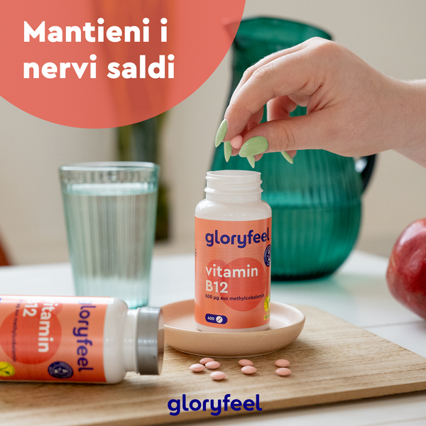 Una mano afferra una bottiglia di Vitamina B12 Metilcobalamina della GloryFeel GmbH Italia, posta su un tavolo con delle mele e un bicchiere d&