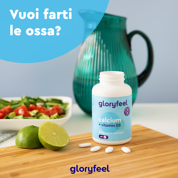 Una bottiglia di Calcio + D3 di gloryfeel Italia è appoggiata su una tavola di legno circondata da lime, insalata e una brocca verde acqua. Il testo italiano chiede: "Vuoi farti le ossa?.