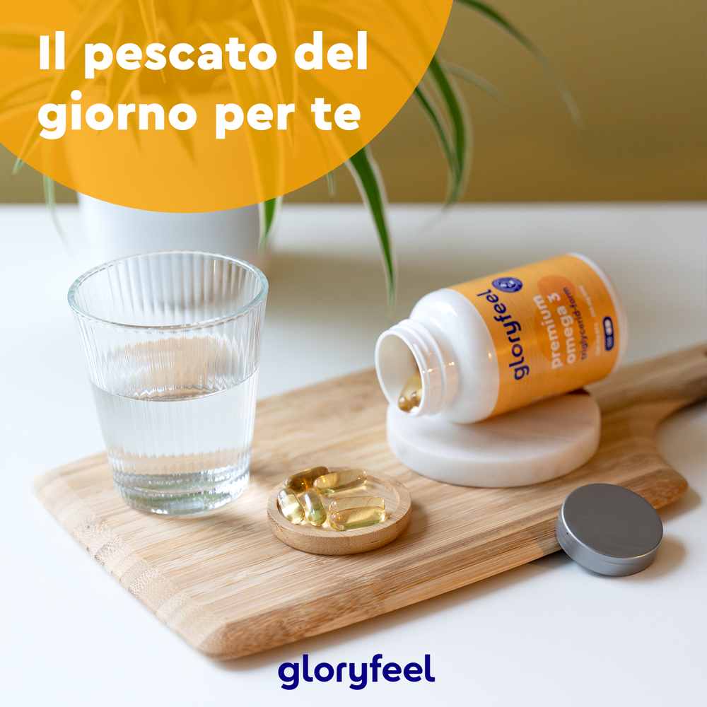 Una bottiglia di capsule Omega 3 Premium di GloryFeel GmbH Italia, ricche di acido docosaesaenoico (DHA), è aperta su una tavola di legno accanto a un bicchiere d&