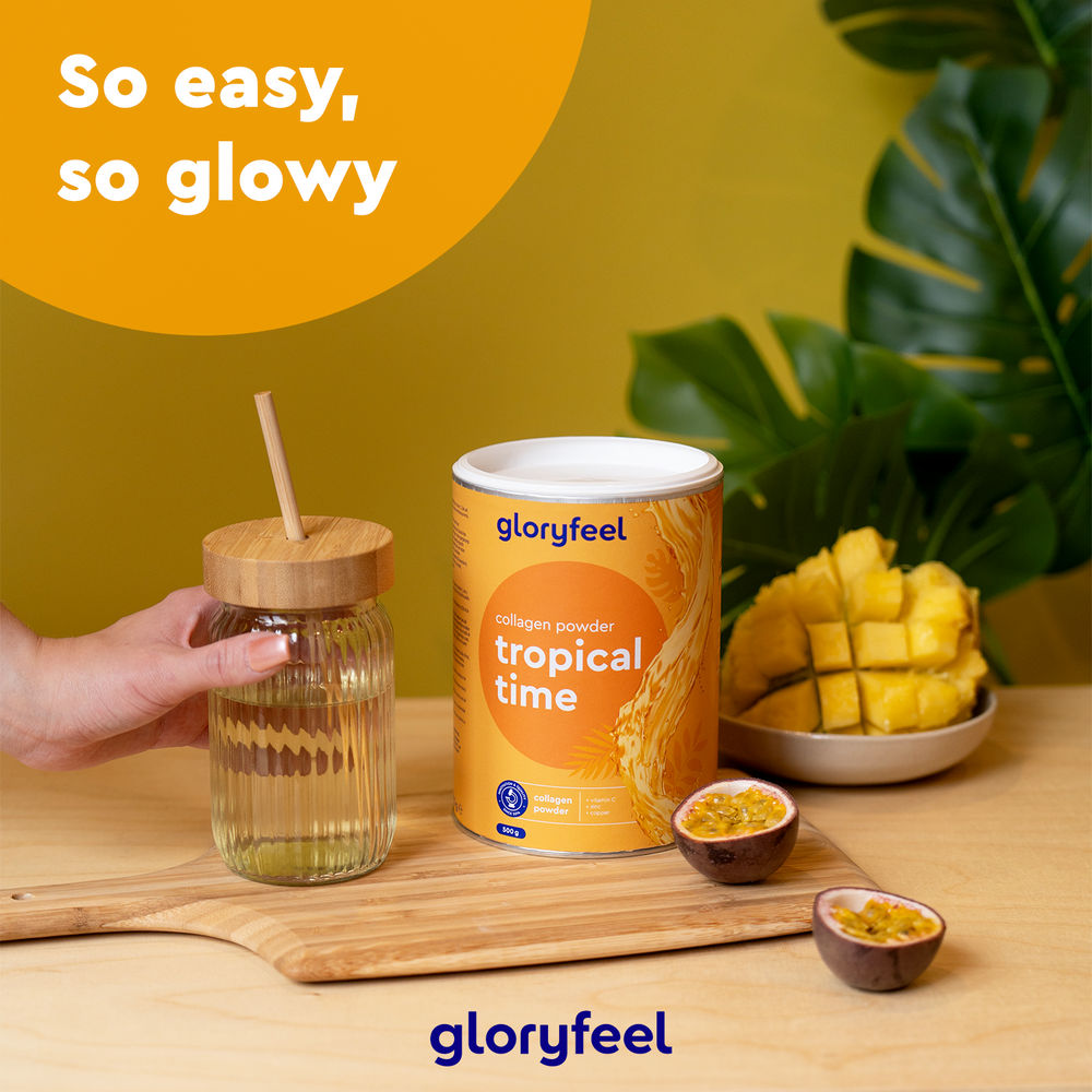Su una tavola di legno è appoggiato un contenitore di &quot;Collagene in polvere - Tropical Time&quot; di gloryfeel Italia, accompagnato da fette di mango, frutti della passione e un barattolo di vetro, il tutto su uno sfondo giallo con foglie verdi.