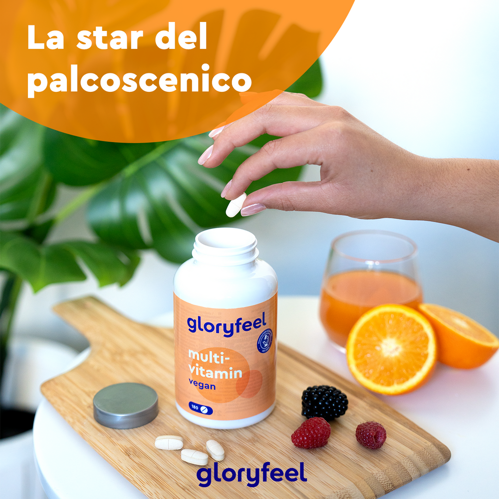 Una mano afferra una pillola da una bottiglia &quot;Multivitaminico in capsule&quot; di GloryFeel GmbH Italy su una tavola di legno con bacche, fette d&