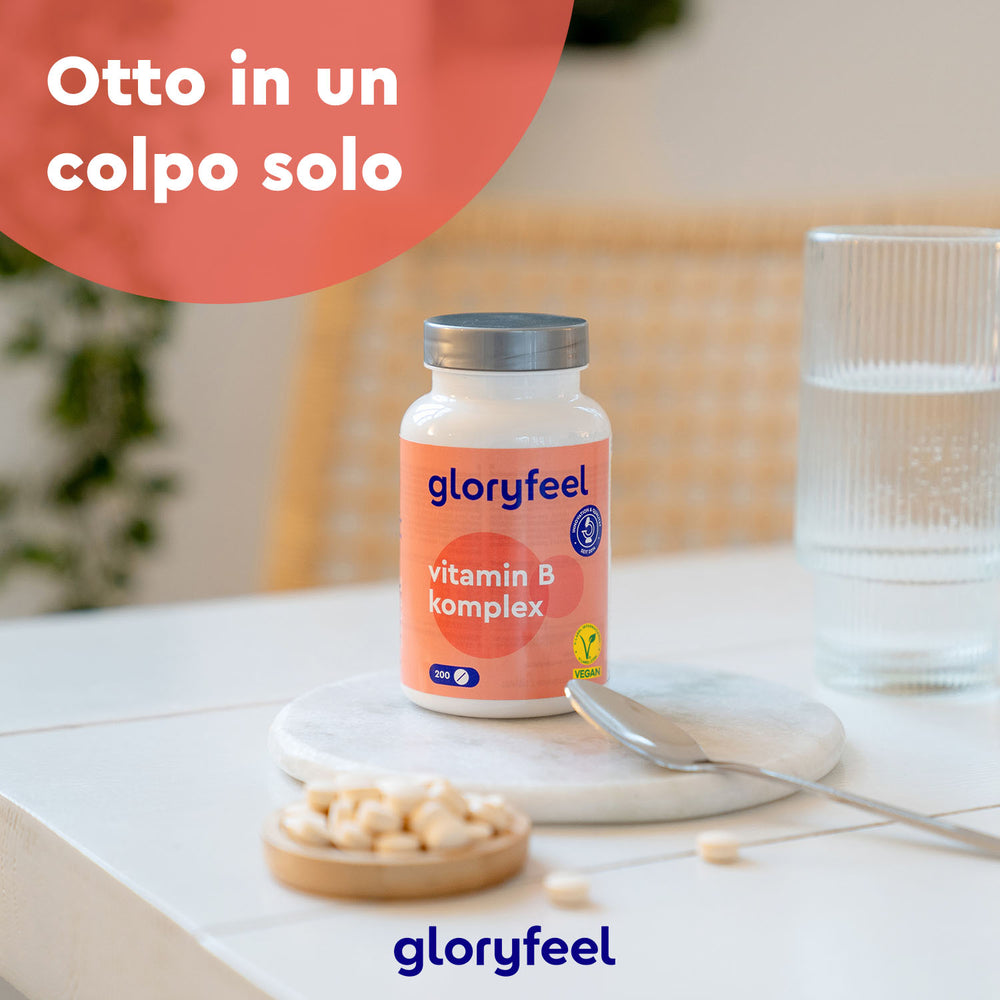 Una bottiglia di Vitamina B Complex di GloryFeel GmbH Italy è appoggiata su un tavolo accanto ad acqua e pillole. Il testo recita &quot;Otto in un colpo solo&quot;, sottolineando il suo ruolo di integratore alimentare approvato dal Ministero della Salute per una dieta equilibrata.