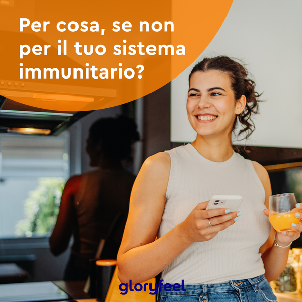 Una persona in cucina, sorridente mentre tiene in mano uno smartphone e un bicchiere di succo d&