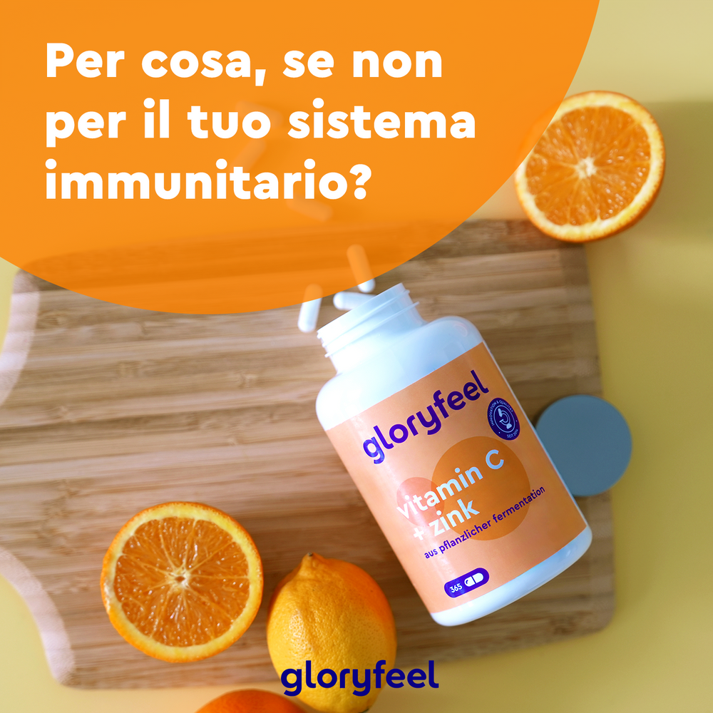 Una bottiglia di Vitamina C + zinco della GloryFeel GmbH Italia è appoggiata su un tagliere di legno con fette di arancia e riporta un testo in italiano che promuove il supporto per le &quot;difese immunitarie&quot;.