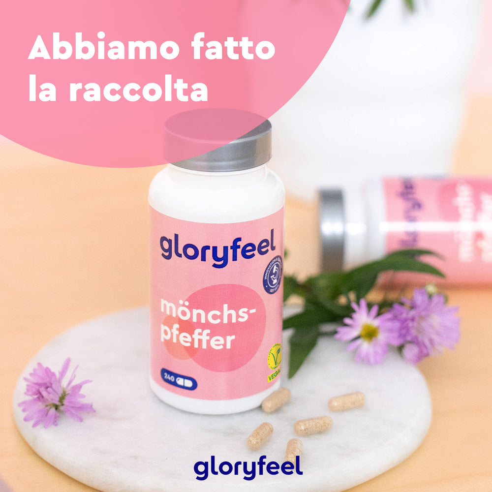 Una bottiglia di integratori alimentari Agnocasto di GloryFeel GmbH Italy è appoggiata su una superficie di marmo con fiori viola e capsule, che ricordano un mix armonioso. Sullo sfondo sfocato, un&