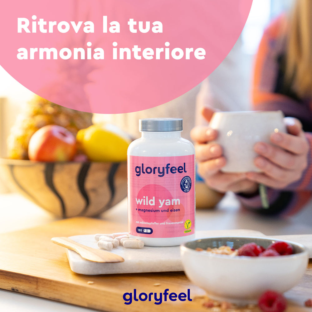 Una bottiglia di integratori Wild Yam - Igname Selvatico di Gloryfeel Italia è appoggiata su un tavolo, accanto a una tazza, una fruttiera e un piatto di capsule.