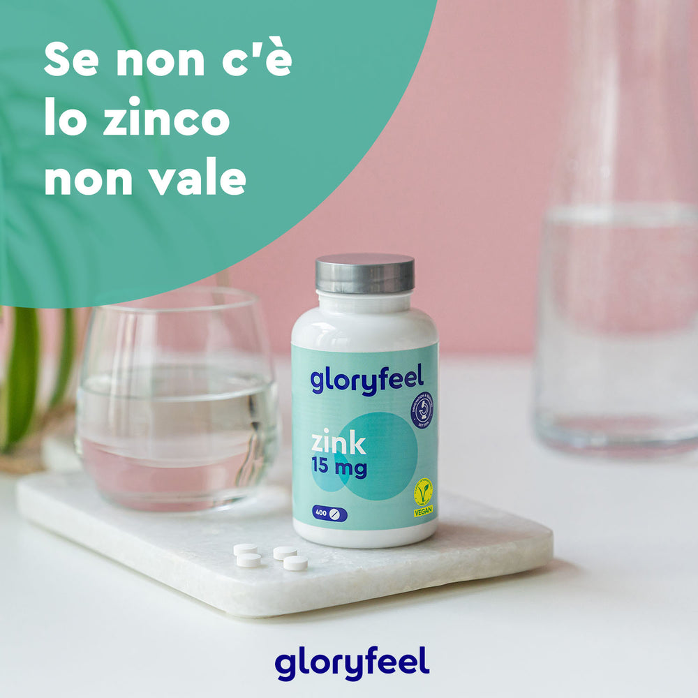 Su una lastra di marmo è appoggiata una bottiglia di Zinco 15 mg in compresse di GloryFeel GmbH Italia, con un bicchiere d&